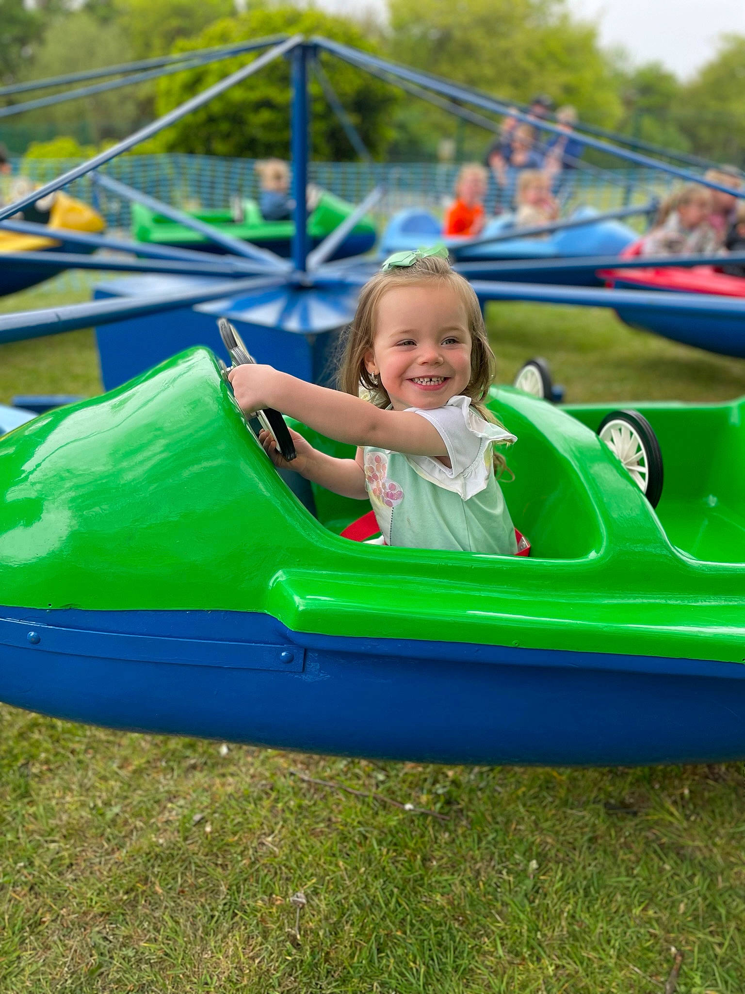 Emmie is registered to the contest to win money with this photo: aerospace_manufacturer, automotive_exterior, boats_and_boating_equipment_and_supplies, bumper, child, chute, fun, grass, joy, leisure, nonbuilding_structure, outdoor_play_equipment, outdoor_recreation, person, plant, play, playground, recreation, smile, toddler