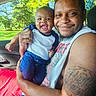 baby, man, smile, tattoo, car, window, greenery, trees, holding, happy, child, casual_clothing, socks, indoor, portrait, parent_and_child, daylight, close_up, family, joy