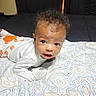 Alexander is registered to the contest to win money with this photo: baby, infant, child, blanket, patterned_blanket, curly_hair, white_clothing, bedroom, indoor, portrait, cute, lying_down, looking_at_camera, young_child, soft_lighting, toddler, face, expression, home, resting