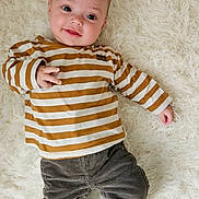 Arthur participe au concours pour gagner de l'argent avec cette photo : baby, casual_clothing, child, comfortable, corduroy_pants, curious, cute, fluffy_rug, hand_gesture, happy, indoor, infant, lying_down, person, portrait, smiling, soft_texture, striped_shirt, white_socks, young_child