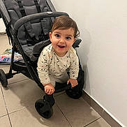 Jannah a rejoint le concours — aidez-le/la à gagner de superbes lots ! toddler, child, stroller, indoor, smiling, happy, flooring, tile, wall, baby, clothing, person, playful, curious, hands, face, head, wheel, seat, casual