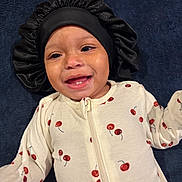 Nalanni joined the competition — help win amazing prizes! baby, child, infant, smiling, happy, portrait, close_up, face, bonnet, headwear, pajamas, cherry_pattern, clothing, lying_down, indoor, dark_background, blue_blanket, toothless_smile, baby_fashion, adorable