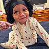 Nalanni is registered to the contest to win money with this photo: child, toddler, baby, portrait, smiling, bonnet, pajamas, cherry_pattern, sitting, carpet, bedroom, dresser, furniture, toys, cartoon, bee, indoor, close_up, happy, photography