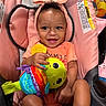 Nalanni is registered to the contest to win money with this photo: baby, child, infant, smiling, portrait, car_seat, pink, headband, bow, plush_toy, caterpillar, rainbow, toy, sitting, indoors, happy, hands, legs, colorful, close_up