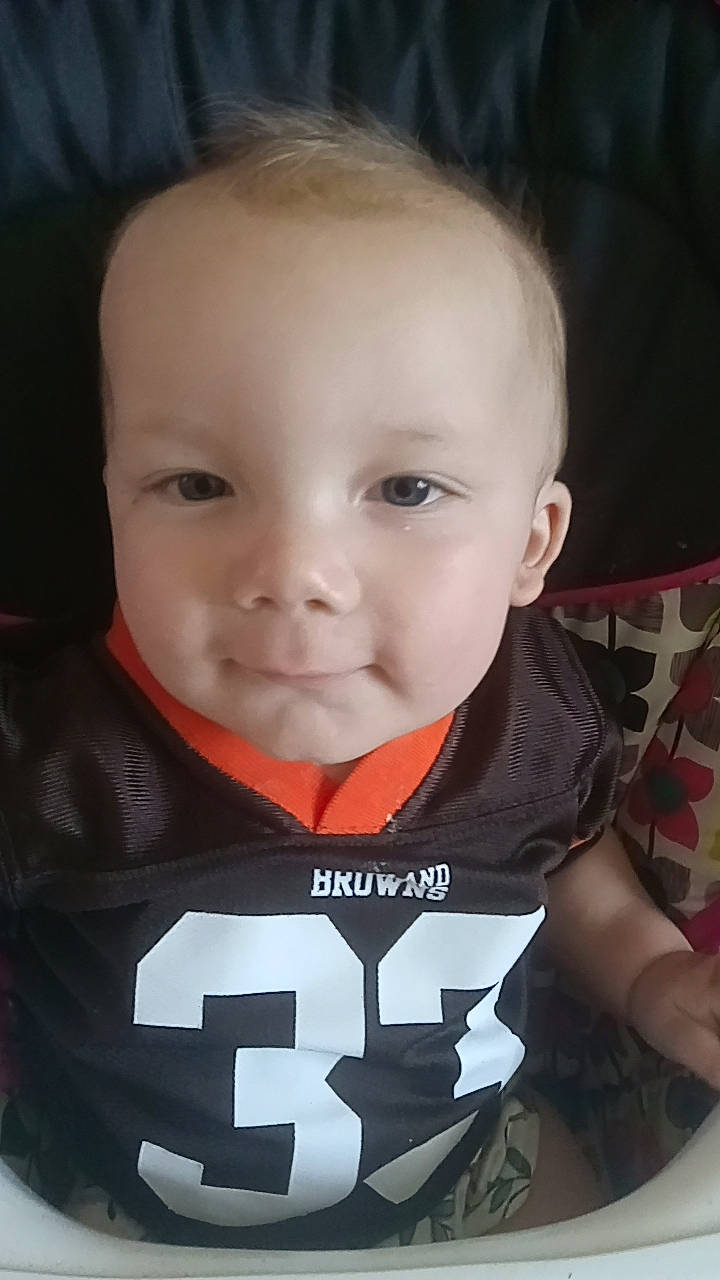 Kolton is registered to the contest to win money with this photo: cheek, cool, eyebrow, facial_expression, fun, human_body, iris, jersey, mammal, mouth, neck, nose, outerwear, person, personal_protective_equipment, sleeve, smile, sports_jersey, t_shirt, toddler