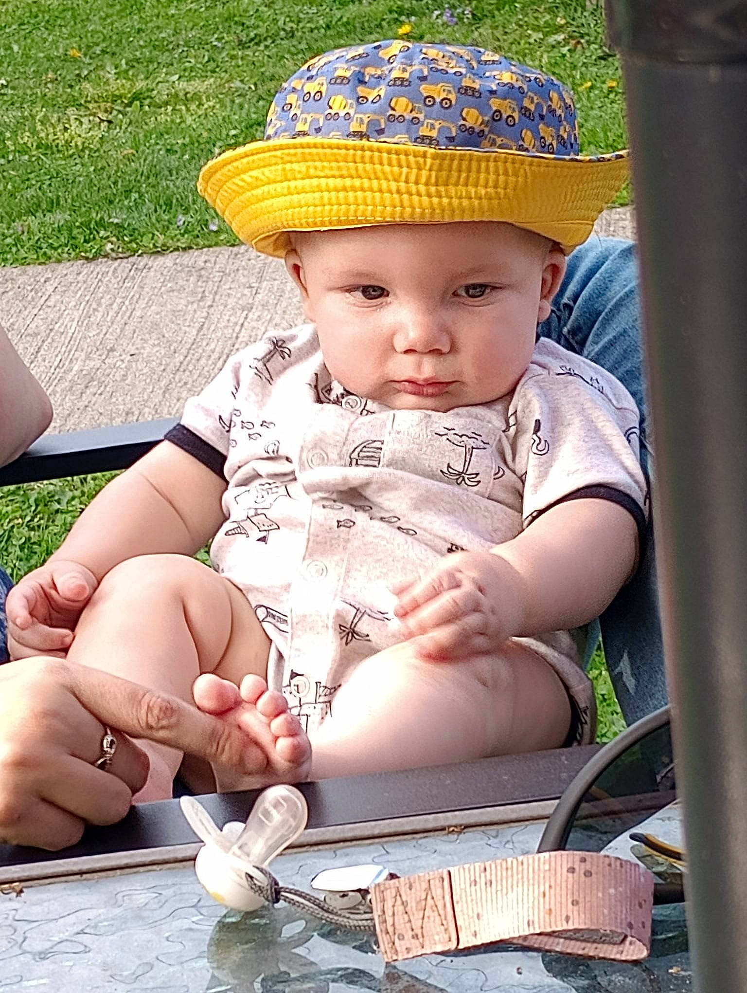 Kolton is registered to the contest to win money with this photo: baby, baby_toddler_clothing, cap, child, eye, fashion_accessory, finger, fun, grass, happy, hat, headwear, human_body, leisure, person, photograph, recreation, sitting, skin, sun_hat