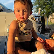 Ethan is registered to the contest to win money with this photo: toddler, child, book, dog_man, outdoor, sunlight, table, car, hand, socks, shirt, greenery, sky, fence, wood, person, face, legs, arm, photography