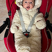 Zoé participe au concours pour gagner de l'argent avec cette photo : baby, infant, car_seat, red, onesie, fluffy_clothing, smiling, happy, child, indoors, seatbelt, toddler, cute, cozy, warm_clothing, face, person, headwear, floor, tile