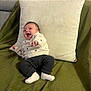 Zoé participe au concours pour gagner de l'argent avec cette photo : baby, infant, smiling, sweater, pants, socks, pillow, blanket, green, white, happy, lying, cozy, indoor, child, cute, portrait, person, relaxing, home