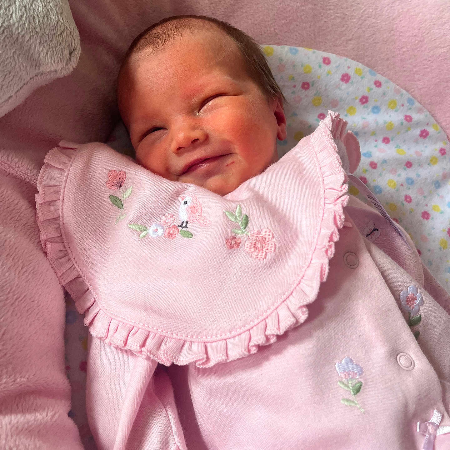 Layla joined the competition — help win amazing prizes! baby, bib, blanket, child, closeup, cozy, cute, embroidered_flowers, head, indoor, infant, newborn, peaceful, pink_clothing, plush, portrait, resting, sleepy, smiling, soft_texture