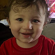 Kai is registered to the contest to win money with this photo: toddler, child, smiling, curly_hair, red_shirt, indoor, portrait, face, happy, person, clothing, wall_art, moon_phases, background, television, light, young_child, casual, cute, expression