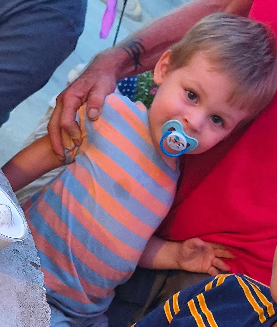 Jasiah joined the competition — help win amazing prizes! child, toddler, pacifier, striped_shirt, orange, gray, adult_hand, red_shirt, curious, outdoor, evening_light, portrait, person, casual_clothing, holding_hand, closeup, face, young_child, cute, gentle