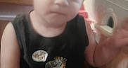 Jaycob is registered to the contest to win money with this photo: arm, black_shirt, blur, casual_clothing, child, close_up, expression, face, furniture, gesture, giraffe_graphic, hair, indoor, person, plastic_toy, sitting, skin, toddler, wooden_cabinet, young_child