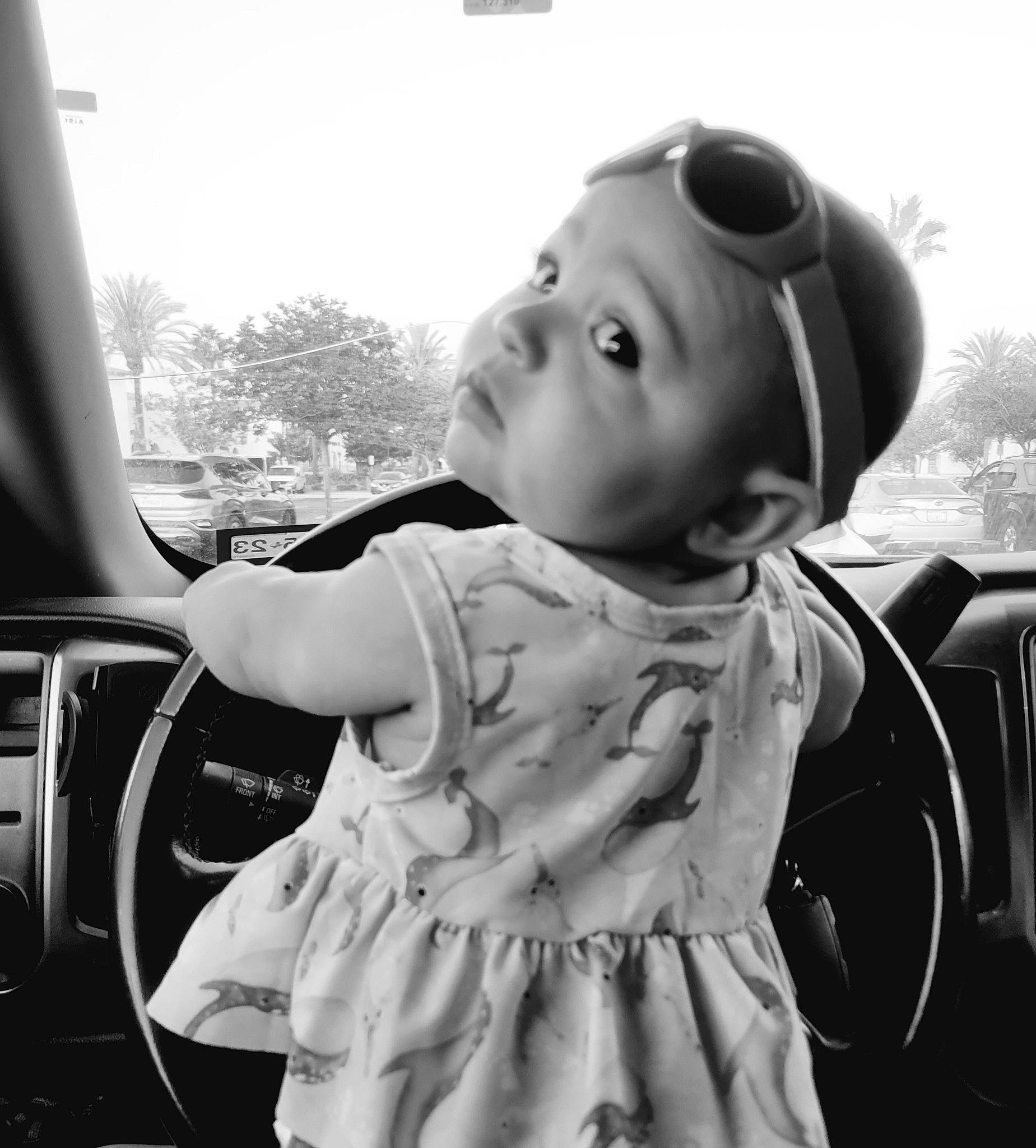Davina is registered to the contest to win money with this photo: automotive_design, baby, black, black_and_white, cool, eye, flash_photography, fun, goggles, happy, motor_vehicle, person, product, skin, standing, steering_wheel, style, sunglasses, toddler, vehicle_door