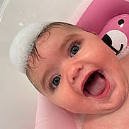 Naveah is registered to the contest to win money with this photo: baby, bath, foam, pink, bathtub, water, child, happy, smiling, face, skin, wet, blue_eyes, head, cute, infant, playful, foam_hat, tub, joyful