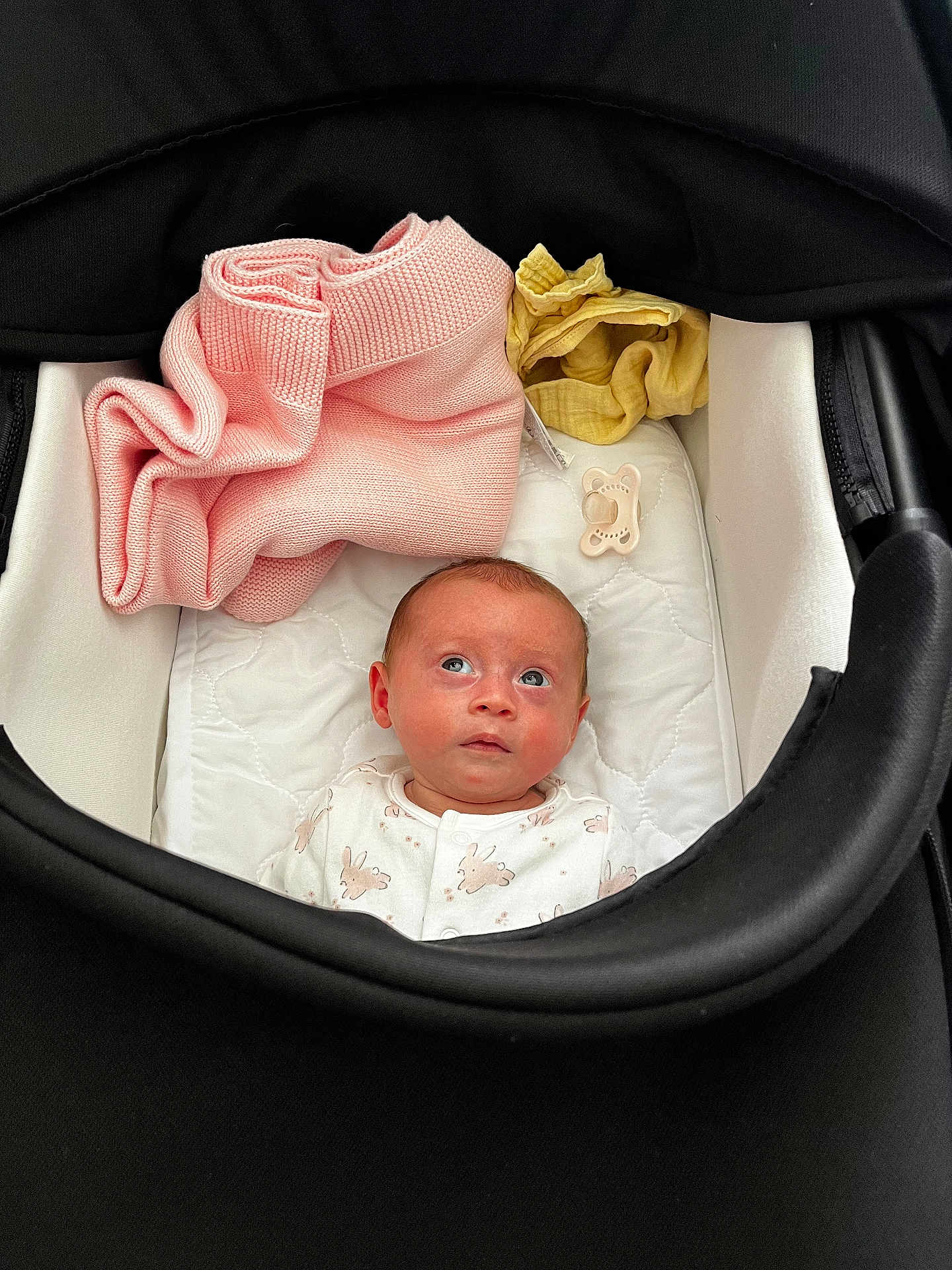 Clara joined the competition — help win amazing prizes! baby, infant, stroller, blanket, pacifier, clothing, face, head, soft, cute, newborn, child, resting, indoors, comfort, looking_up, white, pink, yellow, black