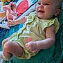 Marian is registered to the contest to win money with this photo: baby, smiling, green_clothing, blanket, toy, stuffed_animal, playmat, indoor, child, person, happy, cute, infant, lying_down, soft_toys, colorful, toddler, face, cheerful, playtime