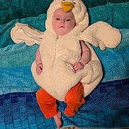Marian joined the competition — help win amazing prizes! baby, costume, chicken_costume, orange_pants, towel, blue_towel, carpet, floor, barefoot, toenails, painted_nails, infant, cute, indoors, lying_down, plush, person, child, headwear, soft_texture