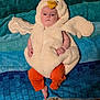 baby, costume, chicken_costume, orange_pants, towel, blue_towel, carpet, floor, barefoot, toenails, painted_nails, infant, cute, indoors, lying_down, plush, person, child, headwear, soft_texture