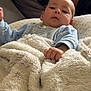 baby, blanket, blue_clothing, couch, curious, face, family, fuzzy_texture, hand, home, indoor, infant, person, portrait, relaxing, resting, soft, toddler, warm, young_child