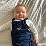 baby, blanket, boy, casual_clothing, child, comfortable, cute, face, happy, indoors, infant, lying_down, navy_blue, overalls, portrait, small_hand, smiling, soft_light, texture, white_shirt
