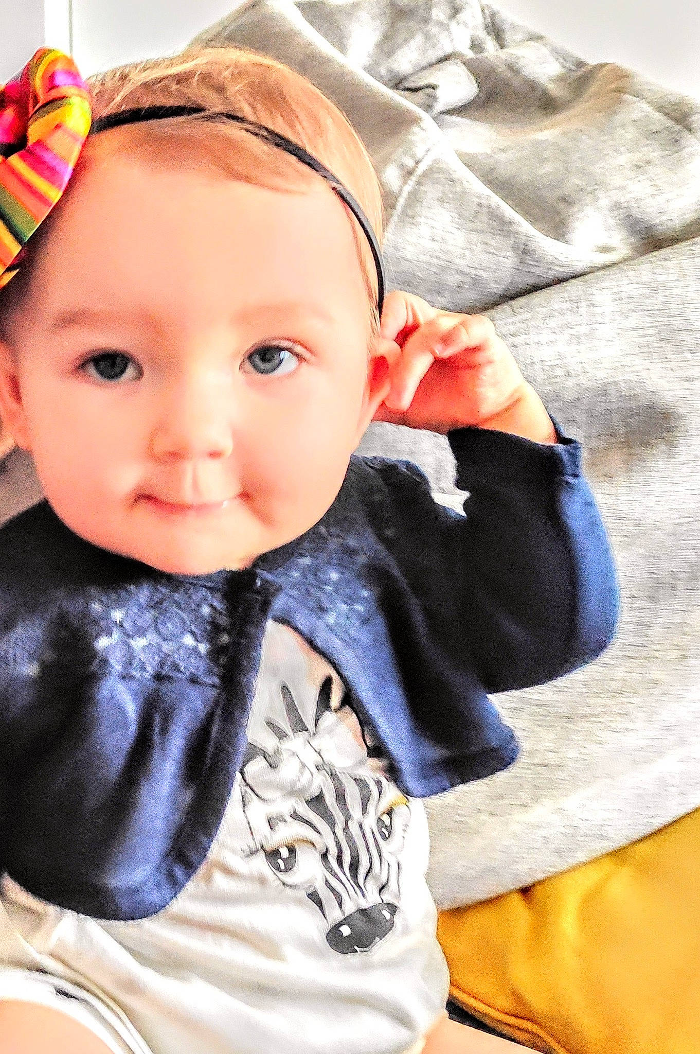 Lilah a rejoint le concours — aidez-le/la à gagner de superbes lots ! baby, baby_toddler_clothing, brown_hair, cheek, child, comfort, cool, electric_blue, eyebrow, eyelash, fashion_accessory, happy, linens, lip, outerwear, pattern, person, sitting, sleeve, textile