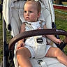 Kristina is registered to the contest to win money with this photo: toddler, child, stroller, outdoor, baby, white_clothing, hair_bows, shoes, grass, tree, park, sunlight, seatbelt, serious_expression, person, baby_stroller, summer, daylight, nature, casual