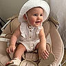 baby, child, smiling, white_hat, romper, baby_rocker, beige, sandal, indoor, curtain, happy, cute, infant, seat, comfort, natural_light, person, portrait, small_child, clothing