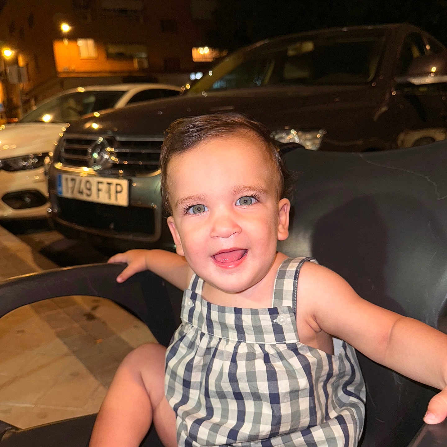 Ilia is registered to the contest to win money with this photo: baby, background, car, chair, child, cute, expression, face, happy, light, night, outdoor, parking, person, romper, seat, skin, smile, toddler, urban