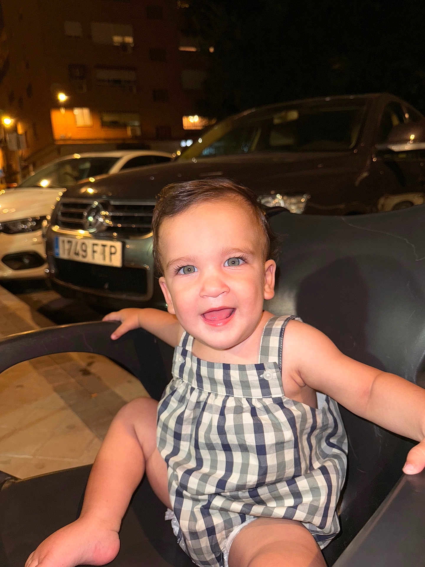 Ilia is registered to the contest to win money with this photo: toddler, child, smile, happy, chair, outdoor, night, urban, car, parking, romper, person, face, cute, baby, skin, seat, expression, light, background