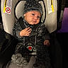 baby, infant, child, car_seat, safety_harness, hat, winter_clothing, fuzzy_outfit, gray_clothing, seated, portrait, face, serious_expression, looking_at_camera, hand, vehicle_interior, car, cushioned_seat, warning_label, safe_travel