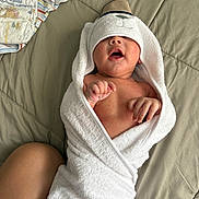 Zealan joined the competition — help win amazing prizes! newborn, baby, infant, lying_down, towel, hooded_towel, hat, yawning, face, hands, bare_chest, swaddled, blanket, bed, quilt, diaper, baby_clothes, striped_clothing, indoor, portrait