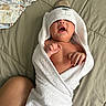 newborn, baby, infant, lying_down, towel, hooded_towel, hat, yawning, face, hands, bare_chest, swaddled, blanket, bed, quilt, diaper, baby_clothes, striped_clothing, indoor, portrait