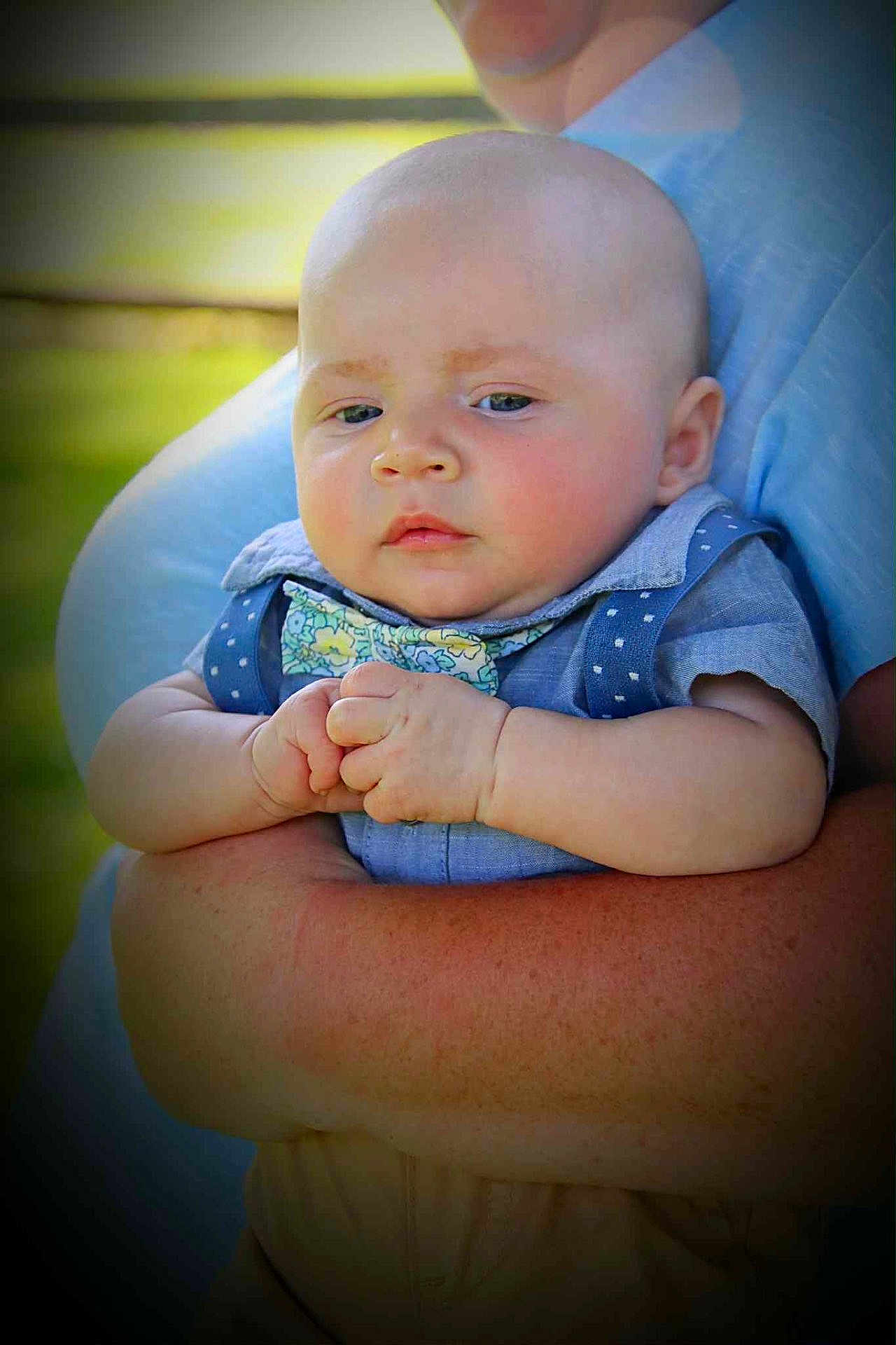 Isaiah is registered to the contest to win money with this photo: baby, child, person, arms, blue_clothing, bow_tie, outdoor, portrait, face, skin, holding, close_up, infant, expression, hands, young, cute, summer, casual, care