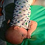 baby, infant, onesie, truck_pattern, padded_mat, lying_down, thumb_sucking, soft_light, indoor, child, cute, sleepy, skin, head, arm, leg, foot, clothing, patterned_clothing, peaceful