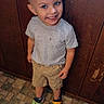 Stefan is registered to the contest to win money with this photo: child, boy, toddler, smiling, portrait, standing, indoors, wood_paneling, patterned_floor, gray_shirt, shorts, sneakers, clogs, cartoon_shoes, blue_eyes, blond_hair, happy, casual_clothing, full_body, photography