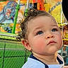 Prynce joined the competition — help win amazing prizes! baby, child, infant, portrait, face, serious, rosy_cheeks, curly_hair, blue_eyes, white_shirt, bib, outdoor, fairground, amusement_park, colorful_lights, ferris_ride, chain_link_fence, summer, close_up, person