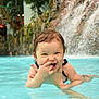 toddler, child, pool, water, splash, wet_hair, playful, smiling, waterfall, outdoor, summer, fun, happy, person, swimming, cute, nature, recreation, leisure, portrait