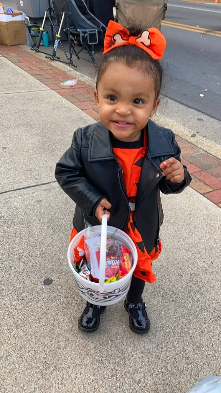 Davina joined the competition — help win amazing prizes! asphalt, baby, baby_carriage, baby_products, child, costume, event, face, fun, joy, orange, people, person, public_event, recreation, road, road_surface, smile, street, tire