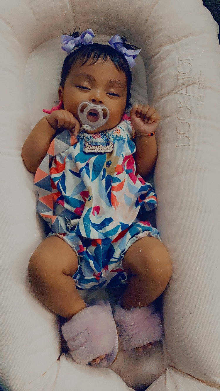 Davina is registered to the contest to win money with this photo: arm, azure, baby, baby_toddler_clothing, blue, child, comfort, dress, face, finger, happy, head, human_body, mouth, pattern, person, skin, sleeve, textile, thigh