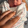 Oakley is registered to the contest to win money with this photo: newborn, baby, sleeping, swaddled, blanket, hospital_blanket, beanie, portrait, close_up, face, indoors, hand, parent, caregiving, peaceful, infant, pink, blue, white, snapchat