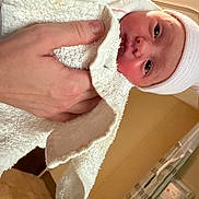 Oakley joined the competition — help win amazing prizes! newborn, baby, infant, child, face, eyes, wide_eyed, blanket, swaddled, hat, textile, hand, adult_hand, portrait, indoors, hospital, nursery, close_up, candid, family