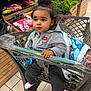 Alya a rejoint le concours — aidez-le/la à gagner de superbes lots ! toddler, child, shopping_cart, grocery_store, blanket, hoodie, nike_logo, black_pants, white_socks, topknot_bun, produce, lettuce, cucumber, floor_tiles, wooden_shelves, plastic_cart, curious_expression, indoor, person, retail