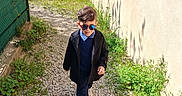 Youcef participe au concours pour gagner de l'argent avec cette photo : blue_pants, boy, casual, child, coat, confident, daylight, fashion, gravel_path, greenery, nature, outdoor, portrait, reflection, shadow, sunglasses, sunlight, walking, wall, white_shoes