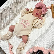 Adalyn is registered to the contest to win money with this photo: newborn, baby, sleeping, pink_bow, knitwear, blanket, pom_poms, cozy, infant, cute, hospital, nursery, wooden_plaque, brush, soft_texture, peaceful, portrait, indoors, baby_clothes, small_person
