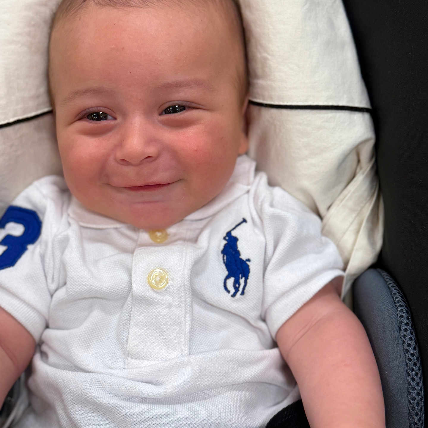 Liam a rejoint le concours — aidez-le/la à gagner de superbes lots ! baby, baby_girl_boy, blue_logo, casual, child, clothing, cute, eyes, face, hand, head, indoor, infant, polo_shirt, portrait, sitting, skin, smiling, white_clothing, young