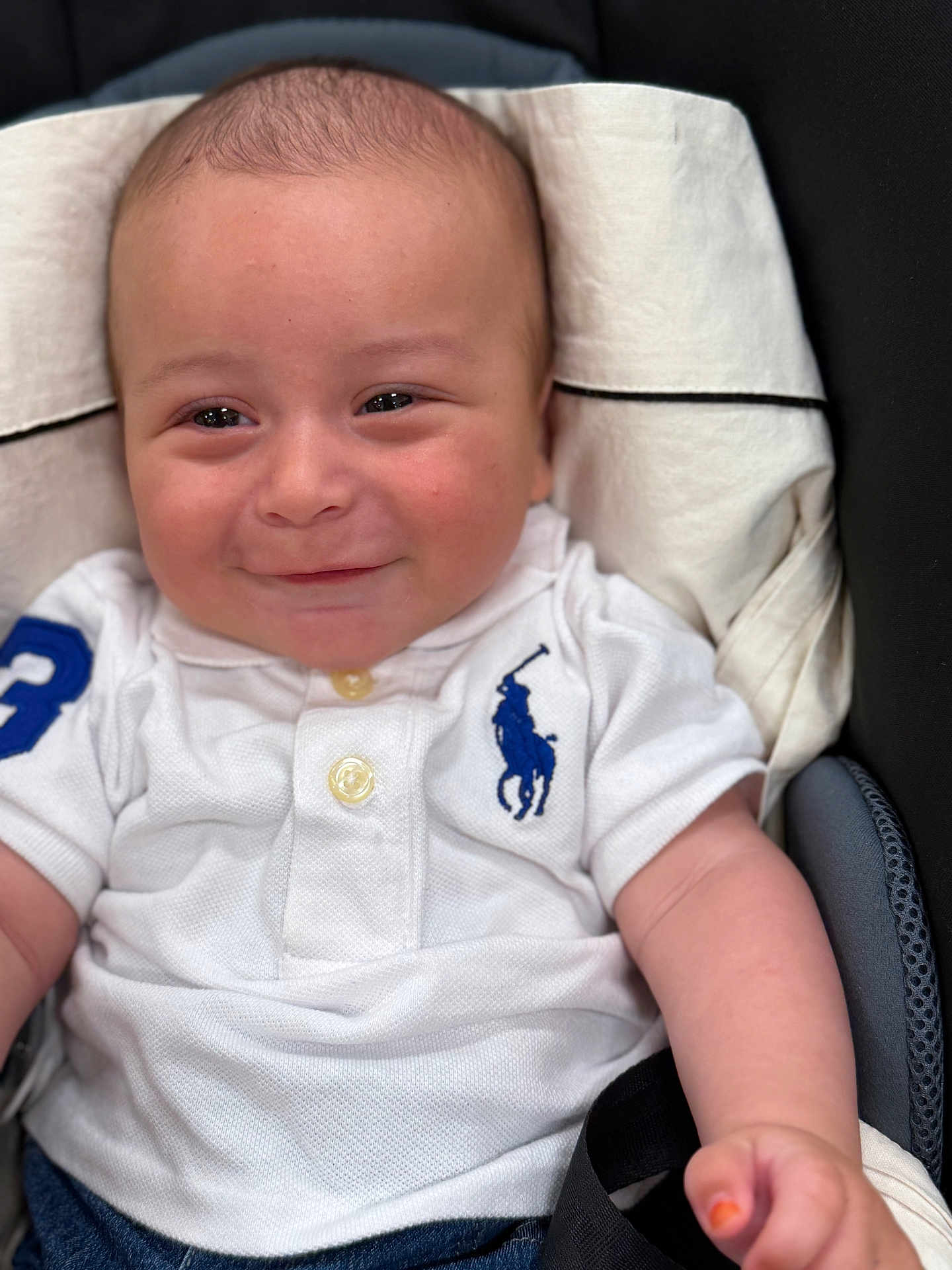 Liam a rejoint le concours — aidez-le/la à gagner de superbes lots ! baby, child, polo_shirt, white_clothing, smiling, face, infant, sitting, cute, portrait, casual, blue_logo, skin, hand, clothing, eyes, head, young, baby_girl_boy, indoor