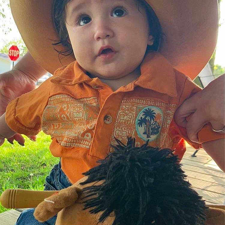 Kruz David Lee Hernandez is registered to the contest to win money with this photo: baby, cap, clothing, costume, cowboyhat, face, grass, hat, head, nature, outdoors, pants, park, person, photography, plant, plush, portrait, sunhat, toy