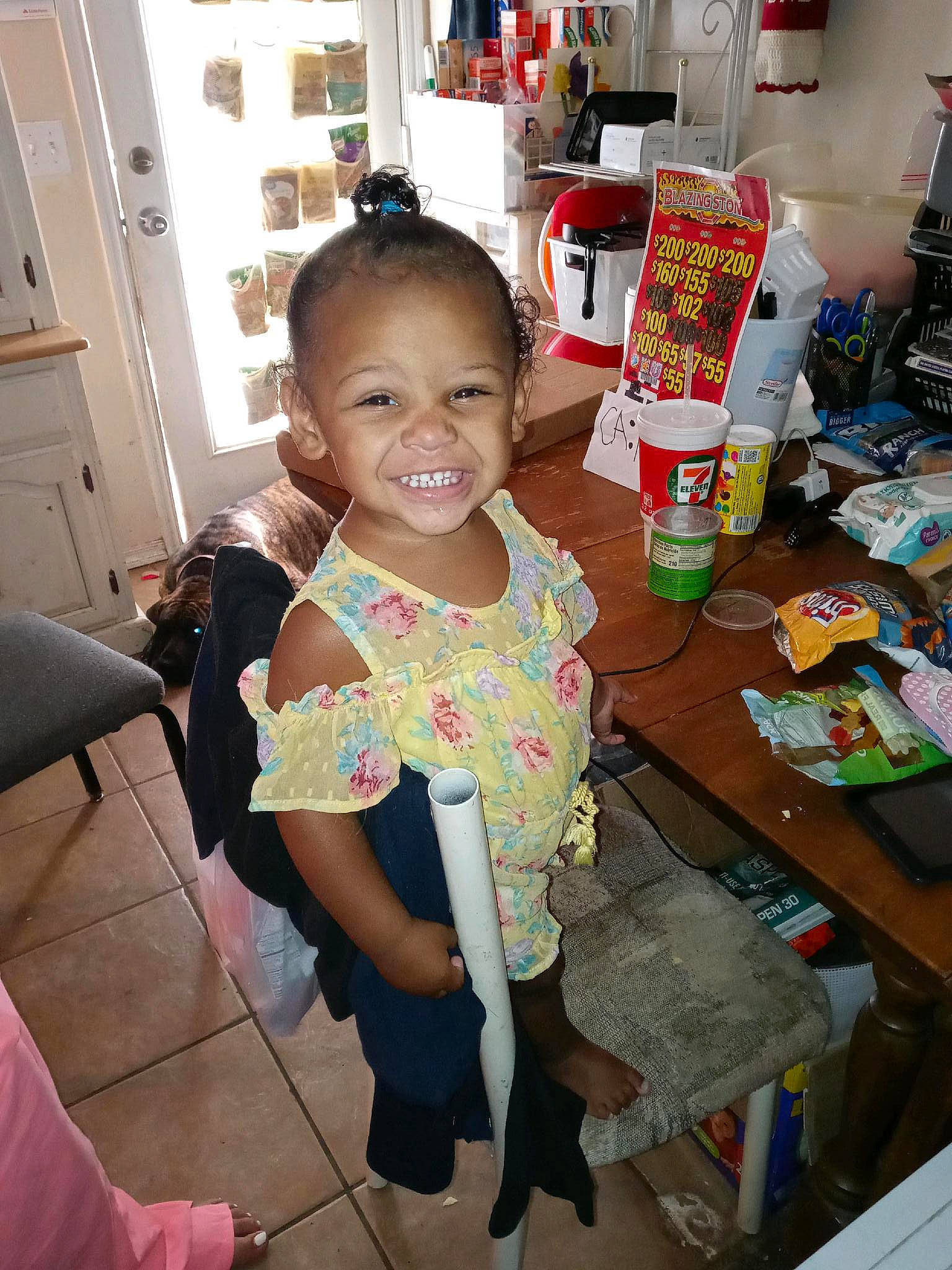 Iyanah is registered to the contest to win money with this photo: baby, baby_toddler_clothing, cabinetry, chair, child, door, event, flooring, fun, hairstyle, happy, human_leg, joy, person, refrigerator, room, skin, smile, t_shirt, table