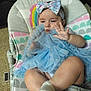 baby, bouncer, bow, carpet, child, chubby_legs, cute, dress, fingers, hand, headband, indoor, pastel_colors, patterned, playful, portrait, rainbow, sitting, socks, tutu